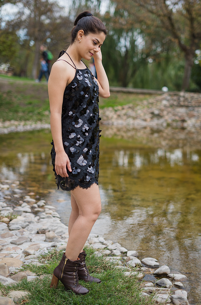 Femme portant une robe à grosses paillettes noire et des bottines